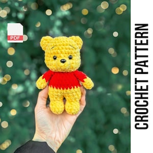 May include: Crochet pattern PDF for a yellow and red Winnie the Pooh amigurumi. The pattern includes instructions for making a crocheted bear with a red shirt.