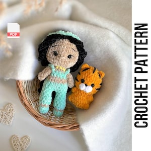 May include: Crochet pattern for a teal and brown amigurumi doll with black hair and a tiger. The doll is wearing a teal outfit with gold accents. The pattern is available as a PDF download.