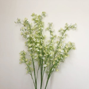 Peut inclure: Un bouquet de fleurs artificielles blanches et vertes avec de petites fleurs délicates. Les fleurs sont disposées en bouquet et ont un aspect naturel et réaliste.