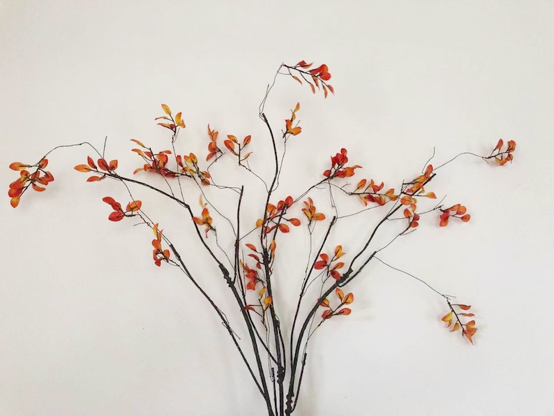 May include: A bouquet of faux branches with orange and yellow leaves. The branches are bare and have a natural, rustic look.