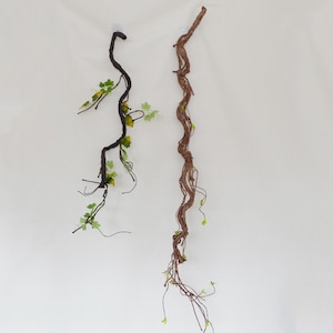May include: Two artificial vine stems with green leaves. The vine on the left is black and the vine on the right is brown.