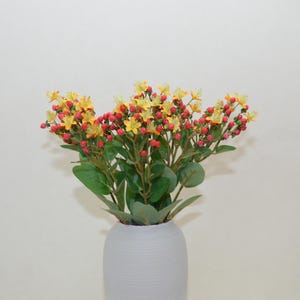 Może przedstawiać: Bukiet sztucznych kwiatów w kolorze żółtym i czerwonym w szarym ceramicznym wazonie.