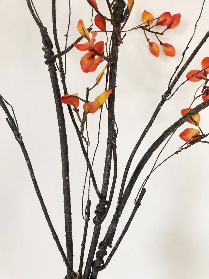 May include: A bouquet of artificial branches with dark brown stems and orange leaves.