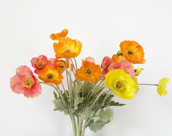 Puede incluir: Un ramo de flores de amapola artificiales en tonos naranja, amarillo y rosa. Las flores tienen pétalos delicados y están dispuestas con follaje verde.