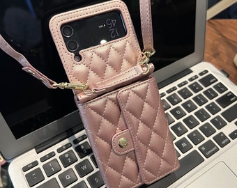 May include: A pink quilted phone case with a matching wallet attached. The case has a gold chain strap and a gold button on the wallet. The phone case has a clear back and the phone screen shows the time 12:45.