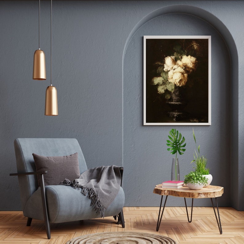 May include: A gray armchair with a throw blanket sits in a room with a wooden coffee table and a framed print of white roses in a vase. The room has a gray wall and a vaulted ceiling.