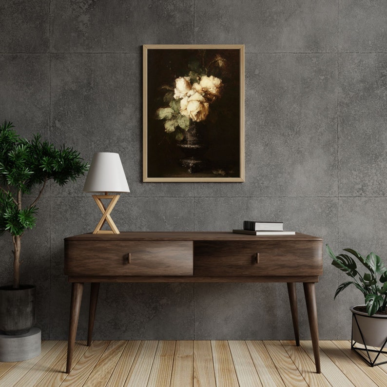 May include: A framed print of a still life painting featuring a bouquet of white roses in a dark vase against a dark background.