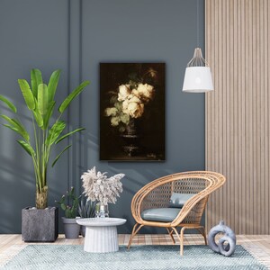 May include: A still life painting of white roses in a vase, hanging on a blue wall in a living room setting with a wicker chair, a potted plant, and a side table.