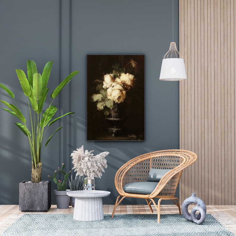 May include: A still life painting of white roses in a vase, hanging on a blue wall in a living room setting with a wicker chair, a potted plant, and a side table.