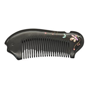 May include: A black comb with fine teeth and a curved handle. The comb is decorated with a floral design in pink, green, and iridescent shell-like material. The comb is designed for hair care.