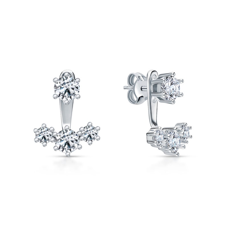 May include: A pair of silver earrings with a single large round clear stone on the top and three smaller round clear stones on the bottom.