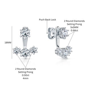 May include: Silver earrings with a push back lock. The earrings feature a total of five round diamonds set in prongs. The larger diamond is 5mm in diameter and the smaller diamonds are 4mm in diameter. The earrings are 18mm long.