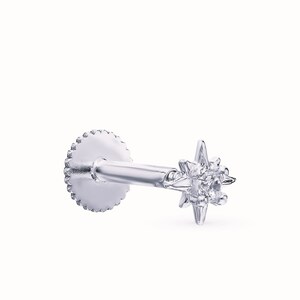 May include: A silver star-shaped stud earring with a single clear gemstone in the center. The earring has a screw-on back.