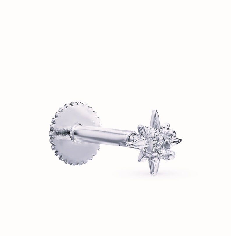 May include: A silver star-shaped stud earring with a single clear gemstone in the center. The earring has a screw-on back.