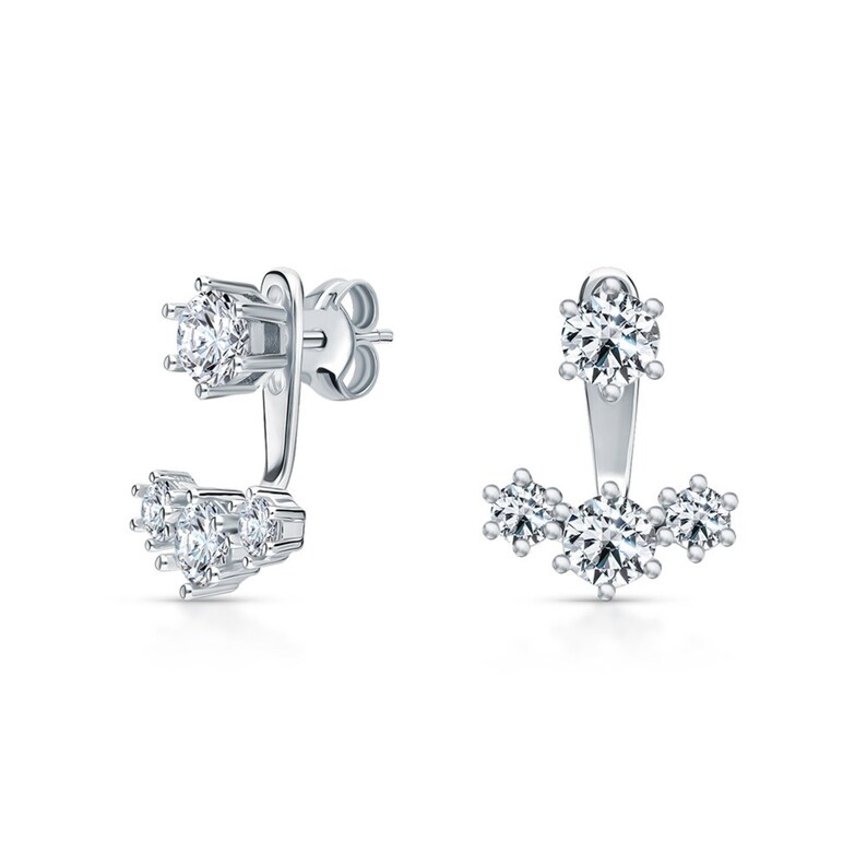 May include: A pair of silver earrings with a single large clear stone on the top and three smaller clear stones on the bottom.