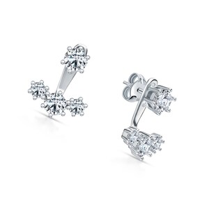 May include: A pair of silver earrings with a cluster of small clear cubic zirconia stones. The earrings have a curved design with a larger stone at the top.