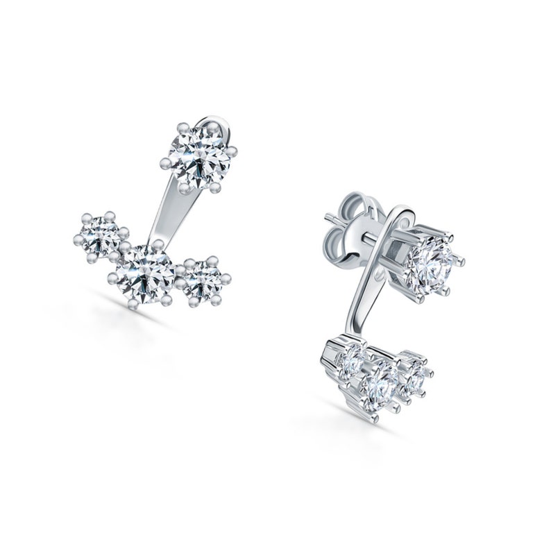 May include: A pair of silver earrings with a cluster of small clear cubic zirconia stones. The earrings have a curved design with a larger stone at the top.