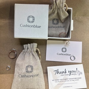 May include: A thank you card with a floral design and the text "Thank you! For your order. We hope you enjoy your purchase! Enjoy 15% off your next order, use code, AGAINIS. Cushionblue LLC."  The card is next to a small white bag with the logo "Cushionblue" printed on it. The bag is next to a small white box with the logo "Cushionblue" printed on it. The box is open and contains a small white bag with the logo "Cushionblue" printed on it.