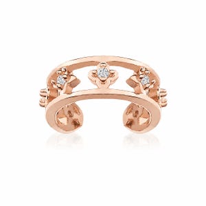 Könnte beinhalten: Ein Ohrklemme aus Roségold mit einem Doppelband-Design, das durch drei blumenförmige Motive verbunden ist. Jedes Blumenmotiv ist mit einem kleinen, klaren, funkelnden Edelstein besetzt. Das Metall hat eine polierte Oberfläche.