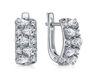 May include: A pair of silver-toned hoop earrings featuring a curved rectangular design. Each earring is encrusted with multiple clear, pear-shaped and round-cut stones arranged in a vertical pattern along the front surface with a secure hinged clasp.