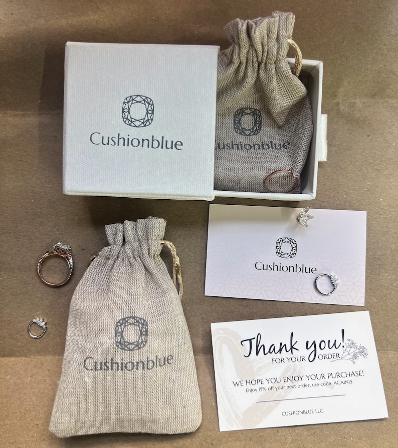 May include: A thank you card with a floral design and the text "Thank you! For your order. We hope you enjoy your purchase! Enjoy 15% off your next order, use code, AGAINIS. Cushionblue LLC."  The card is next to a small white bag with the logo "Cushionblue" printed on it. The bag is next to a small white box with the logo "Cushionblue" printed on it. The box is open and contains a small white bag with the logo "Cushionblue" printed on it.