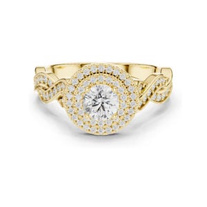 Könnte beinhalten: Ein Ring aus Gelbgold mit einem großen runden Mittelstein, der von einem doppelten Halo aus kleinen weißen Pavé-Diamanten umgeben ist. Die Ringschiene zeigt ein gedrehtes, ineinandergreifendes Design, das beidseitig mit Diamanten besetzt ist.