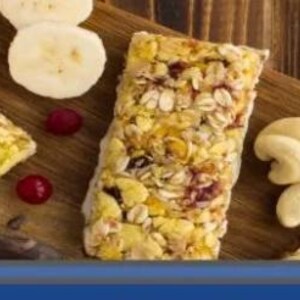 Może przedstawiać: Drewniana deska prezentuje batonik zbożowy, plasterki banana i orzechy nerkowca. Tekst "Actual Size" znajduje się w turkusowym okręgu. Ż&oacute;łte pudełko zawiera napis "Run Bars Burn Fat Cells".