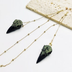 May include: A pair of gold chain glasses retainers with green and black bird skull charms.
