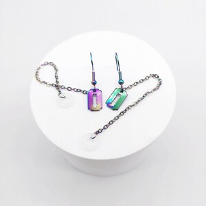 May include: A pair of iridescent rainbow-colored razor blade earrings with a chain and a clear bead on each earring.