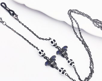 Colar para óculos com pingente de caveira e abelha, em metal preto fosco.