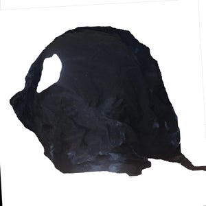 May include: A black rock formation with a large hole in the centre. The rock is weathered and has a rough texture.