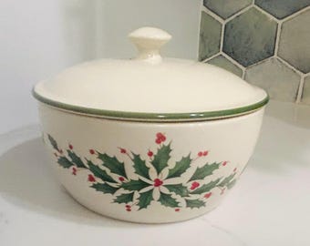 May include: A white ceramic cookie jar with a green and red holly design. The lid has a knob on top.