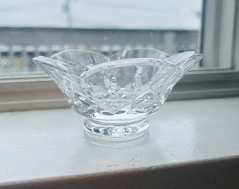May include: A clear glass bowl with a scalloped edge and a cut crystal design. The bowl is sitting on a white windowsill.
