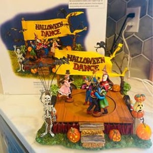 Op de afbeelding: Een geanimeerde muzikale figuurset met Halloween-thema met een draaiende dansvloer, skeletten, pompoenen en een banner met de tekst "Halloween Dance".