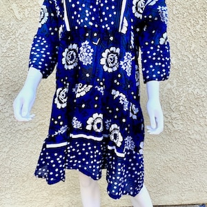 May include: A blue and white patterned dress with a collared neckline and button closure. The dress has a floral and polka dot design.