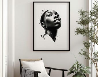 May include: Black and white framed art print of a person looking upwards. The artwork features a detailed portrait with ink splatter effects. The print is displayed on a white wall above a chair with a pillow and blanket, with plants in the foreground.