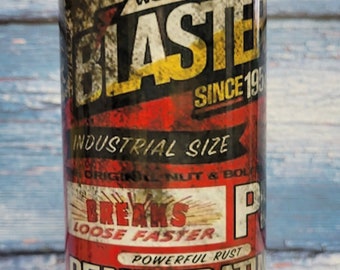 May include: A yellow, red, and black can with the text "BLASTER SINCE 195" and "INDUSTRIAL SIZE" on it. The can is labeled "BREAKS LOOSE FASTER" and "POWERFUL RUST PENETRATING CATALYST". The can is sitting on a wooden surface.