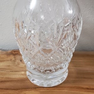 May include: A clear glass vase with a cut crystal design. The vase has a wide mouth and a narrow base.