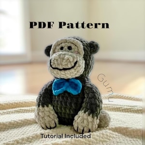 May include: A crochet monkey toy with dark gray fur, a light beige face, and a bright blue bow tie. The text PDF Pattern and Tutorial Included is visible. The monkey has black eyes and a stitched mouth, crafted from thick, textured yarn.