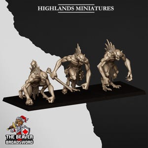 Puede incluir: Tres figuras de fantasía en miniatura beige sobre una base negra. Las figuras son humanoides con rasgos exagerados, posando en acción. El texto "HIGHLANDS MINIATURES" está en la parte superior. El logotipo de Beaver Broadsword está en la parte inferior.