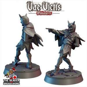 Pode incluir: Uma miniatura pintada de cinza de um demônio vestindo uma capa com capuz e sapatos pontiagudos. O demônio tem chifres e uma expressão travessa. A miniatura está em pé sobre uma base circular.