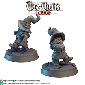 May include: Two grey 3D printed miniature figures of dwarves wearing pointed hats and carrying staffs. The figures are standing on circular bases with a textured surface.