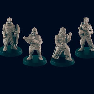 Puede incluir: Cuatro figuras en miniatura de personajes de fantasía, cada una sobre una base verde oscuro. Las figuras son detalladas, representando guerreros con armaduras y empuñando armas, con una paleta de colores neutros.