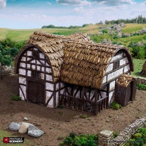 May include: A detailed miniature model of a medieval barn with a thatched roof. The building has a white and brown timber-framed structure and a small outbuilding. The scene is set in a rural landscape with green fields and a blue sky.