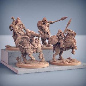 Op de afbeelding: Vier miniatuurfiguren die op geiten rijden, elk met een ander wapen en schild. De figuren zijn in een lichtbruine kleur geverfd en staan in een dynamische actiehoudings.
