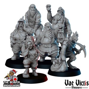 May include: A collection of unpainted miniature fantasy figures, including dwarves and a reptilian creature, standing on black bases. The figures are in various poses, some holding tools and objects. The Beaver Broadsword and Vae Victis Miniatures logos are visible.