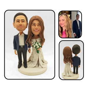 May include: A custom wedding cake topper featuring a bride and groom in a realistic style. The bride is wearing a white dress with lace detailing and holding a bouquet of white flowers. The groom is wearing a blue suit and a white shirt. The couple is standing on a white base.
