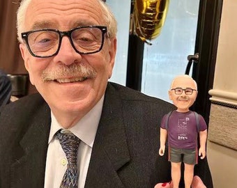 May include: A man in a suit and tie is holding a small figurine of a man wearing a purple shirt, blue shorts, and a backpack. The figurine is holding a sign that says "R&R".