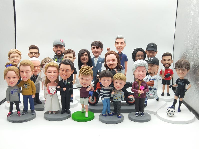 May include: A collection of twenty-one custom bobblehead figurines featuring various individuals in diverse outfits, including a bride and groom, a golfer, a baseball player, and a soccer player, all standing on individual circular bases.