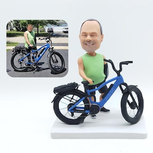 Könnte beinhalten: Figur einer blauen Elektrofahrrads mit schwarzen Reifen und dem Wort "WIRED" auf dem Rahmen. Die Figur enthält eine Miniaturperson mit grünem Tanktop und schwarzen Shorts. Ein eingesetztes Foto zeigt das echte Fahrrad.